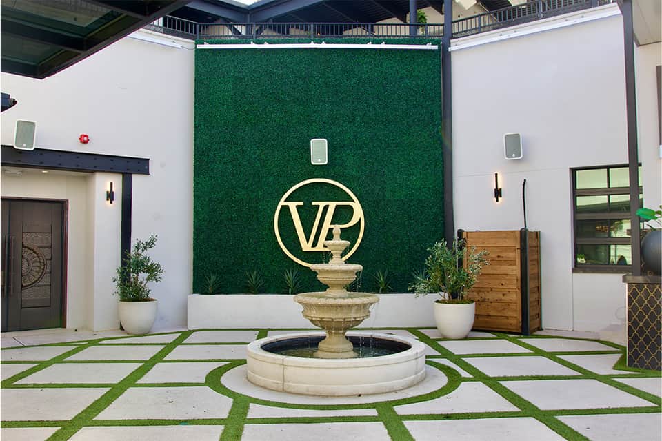 Luxury courtyard entrance with VIP logo, fountain, patterned flooring, and modern architecture