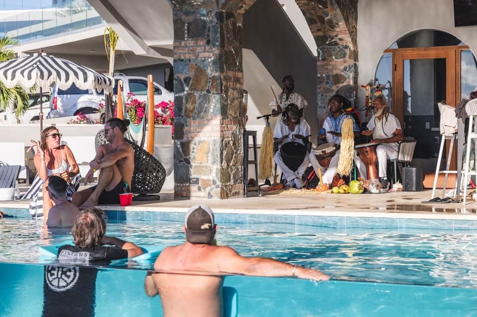 Resort pool with cultural performers entertaining guests during daytime event