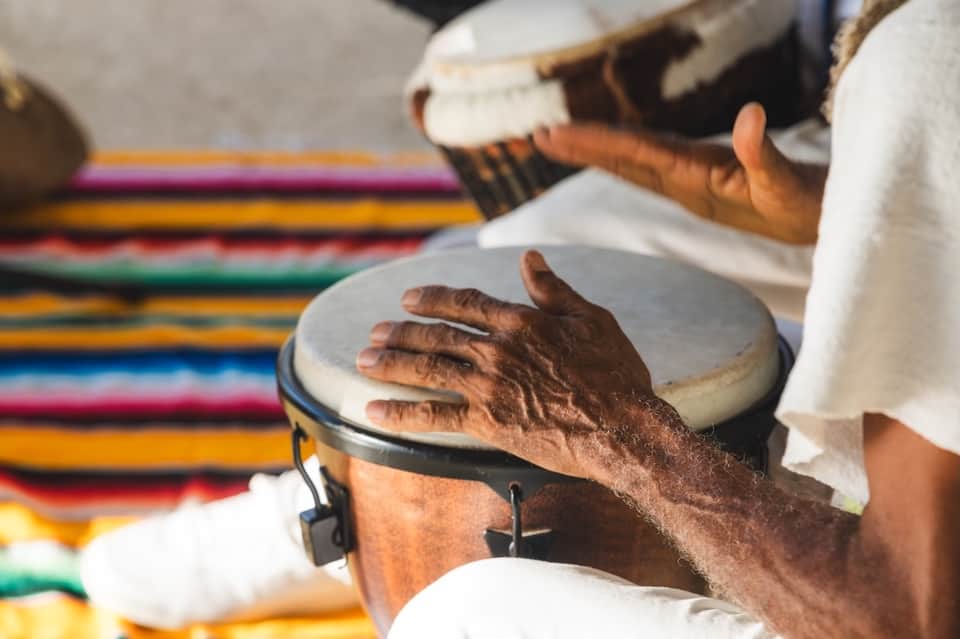 Hands playing traditional drums on colorful woven textile background