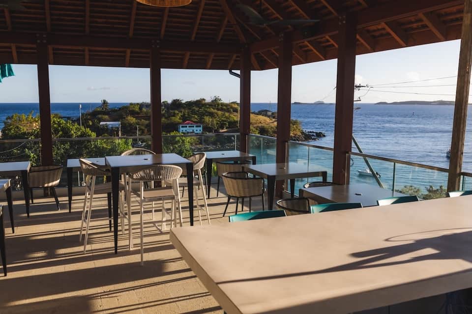 Beachfront restaurant deck with wooden beams, ocean views, and casual dining tables