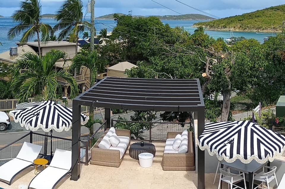 Elevated tropical terrace with striped umbrellas, wicker seating, and ocean view