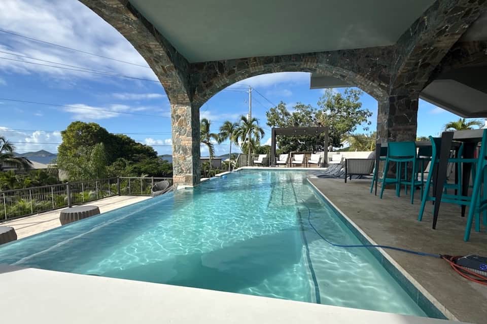 Infinity pool overlooking tropical landscape under covered pavilion structure