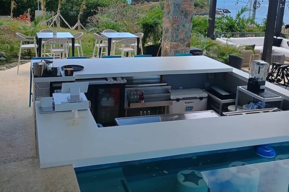 Outdoor kitchen and bar area overlooking tropical landscaping and ocean