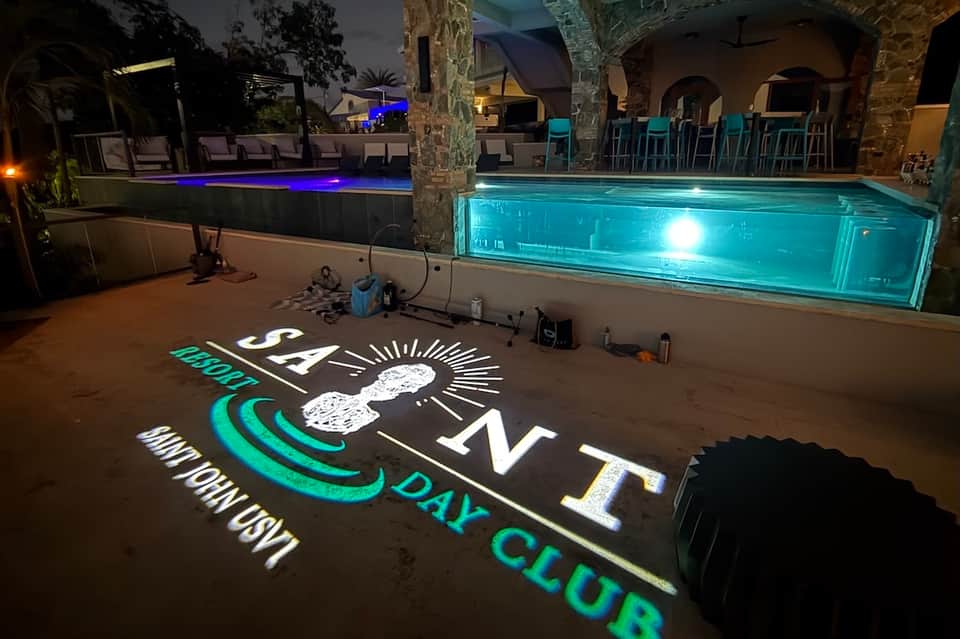 Illuminated nighttime pool area with glowing sign at day club venue