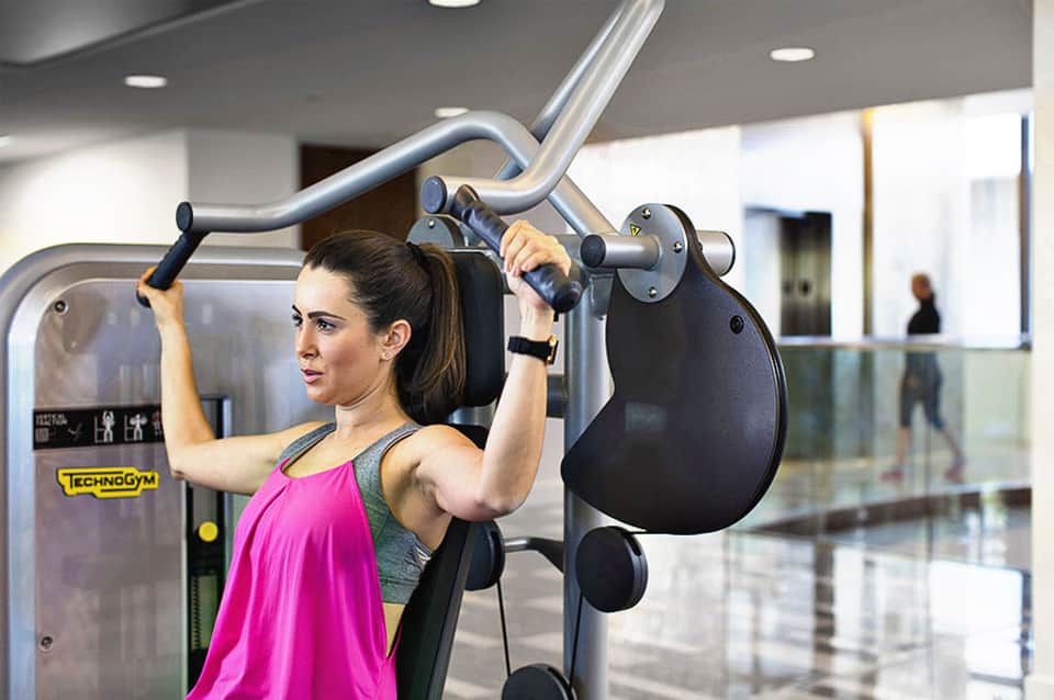 Woman using leg press machine at gym with TechnoGym equipment and modern facility interior