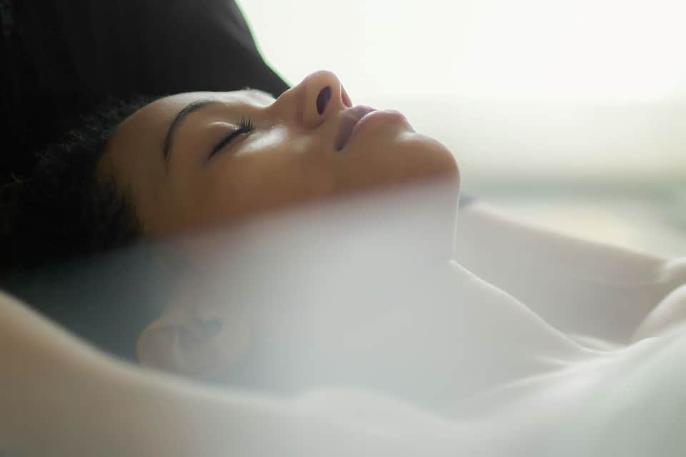 Woman relaxing in spa bathtub with ocean view in background