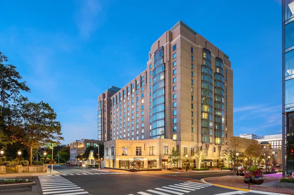 Historic downtown hotel building at twilight with illuminated lower level retail and multi-story brick and glass facade