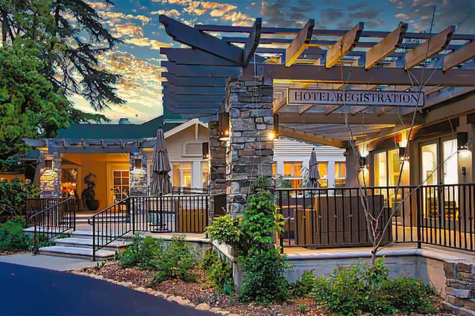 Hotel registration entrance with stone pillar and pergola at dusk with illuminated buildings