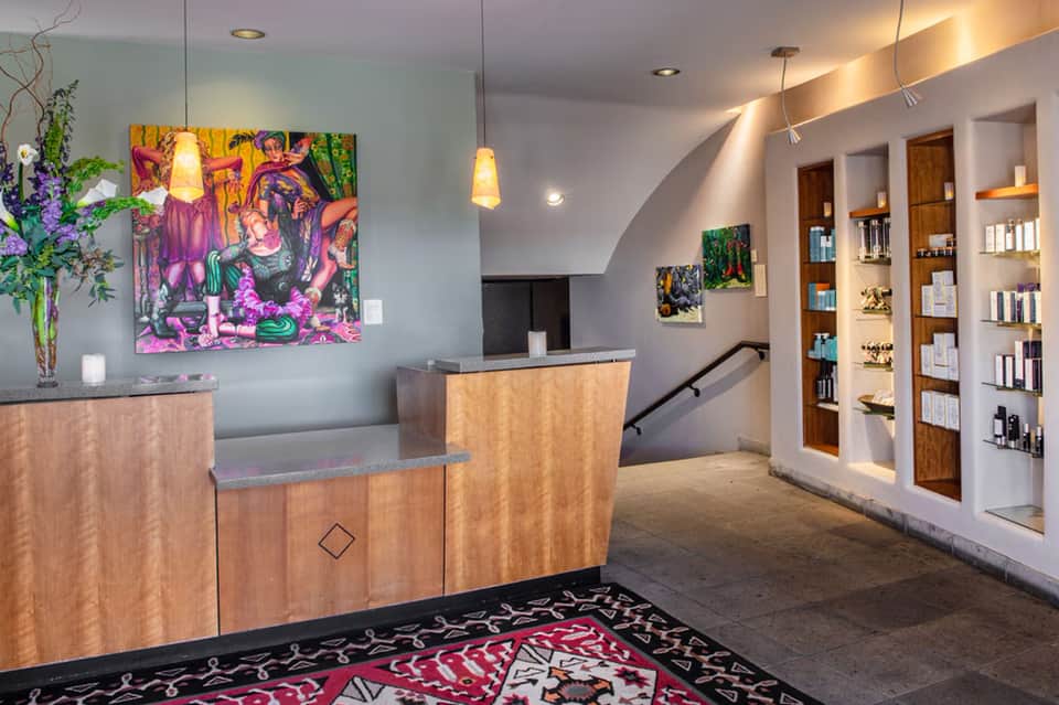 Contemporary hotel lobby with wooden reception desk, vibrant artwork, and retail shelving