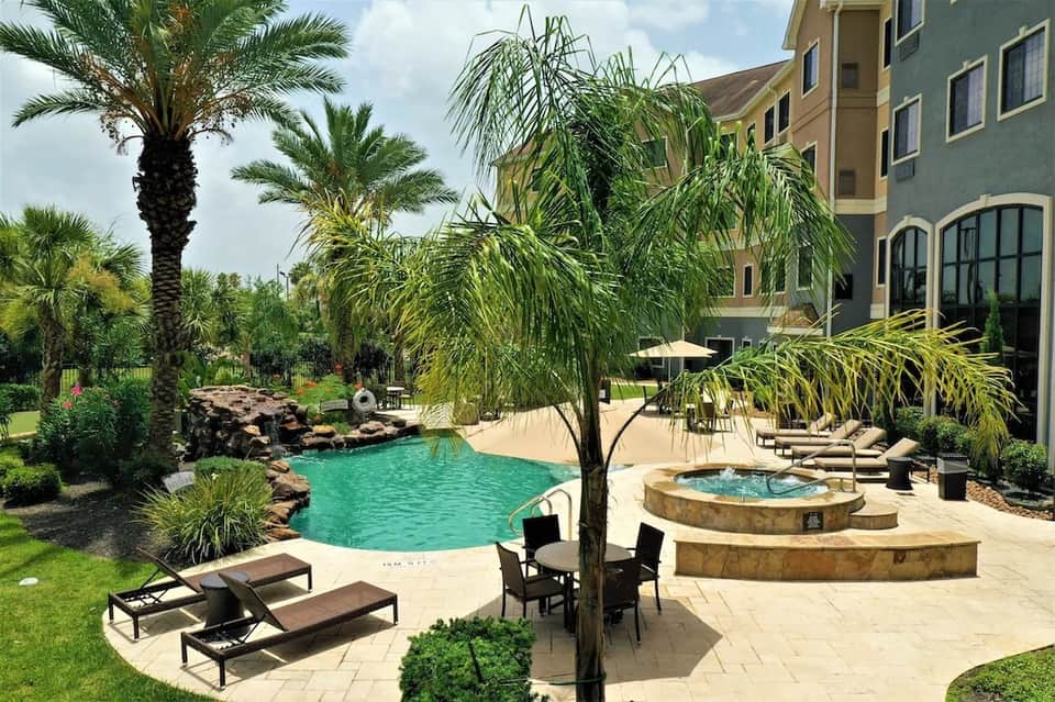 Resort courtyard with lagoon-style pool, hot tub, lounge chairs, and tropical landscaping