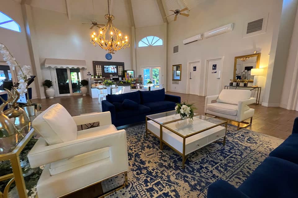 Elegant resort lobby with high ceilings, chandelier, navy and cream seating, and polished wood floors