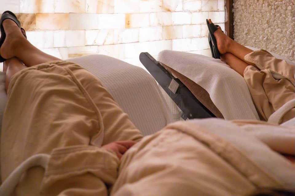 Two people's feet up on bed with ocean view from beachfront hotel room
