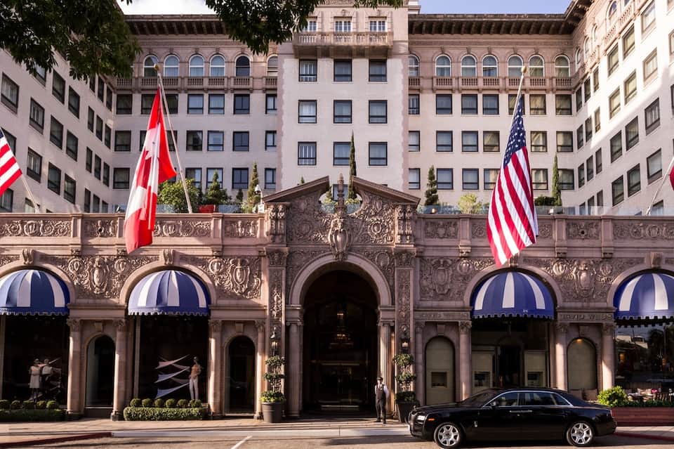 Elegant historic building facade with ornate details, blue awnings, and flags on busy city street