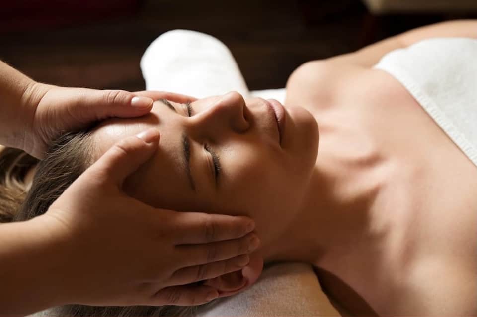 Spa therapist performing facial massage on relaxed client