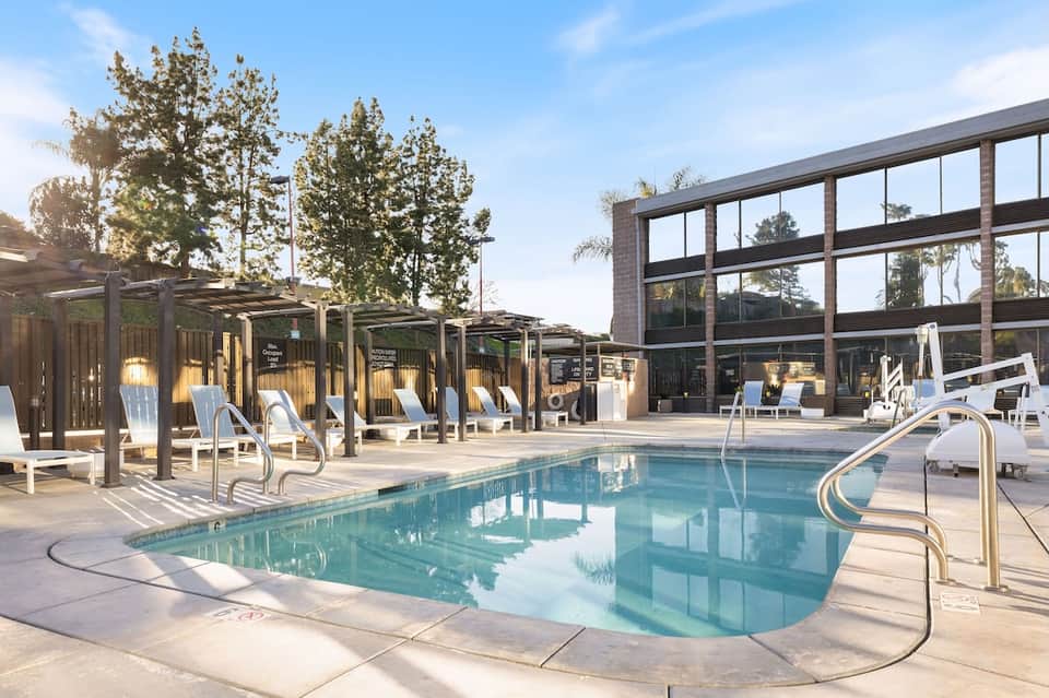 Resort swimming pool with pergola cabanas, loungers, and brick building