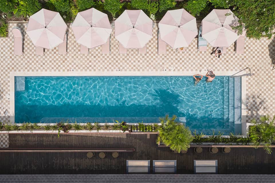 Aerial view of narrow lap pool with pink umbrellas and checkered deck