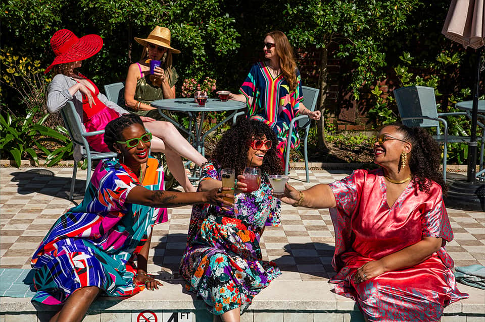 Diverse group celebrating outdoors in bright clothing at resort courtyard with greenery