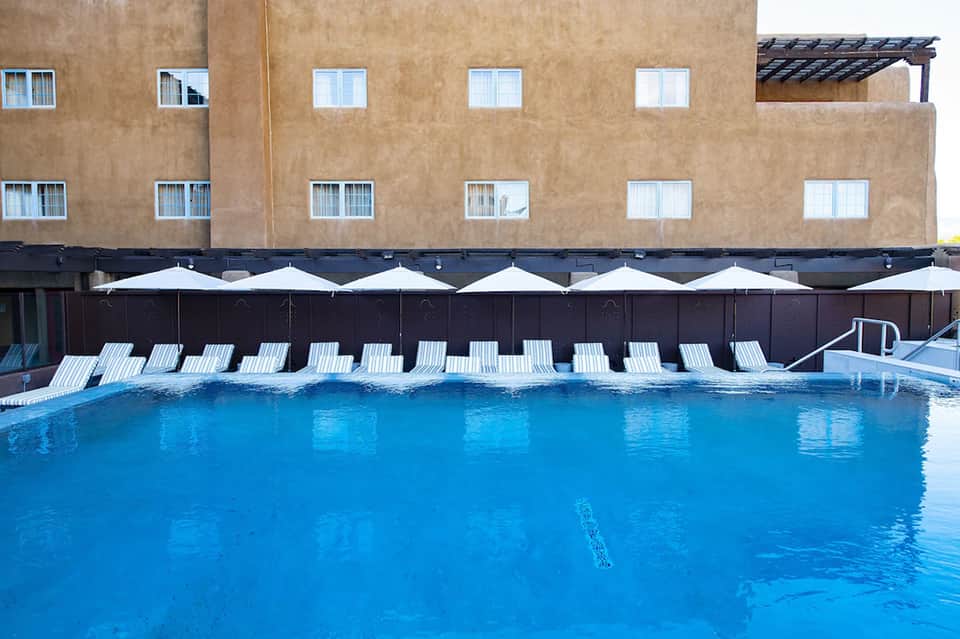 Resort outdoor pool with blue water, white lounge chairs, and beige building backdrop