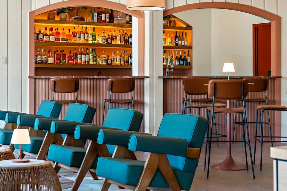 Modern bar and lounge area with wood accents, blue seating, and extensive liquor selection