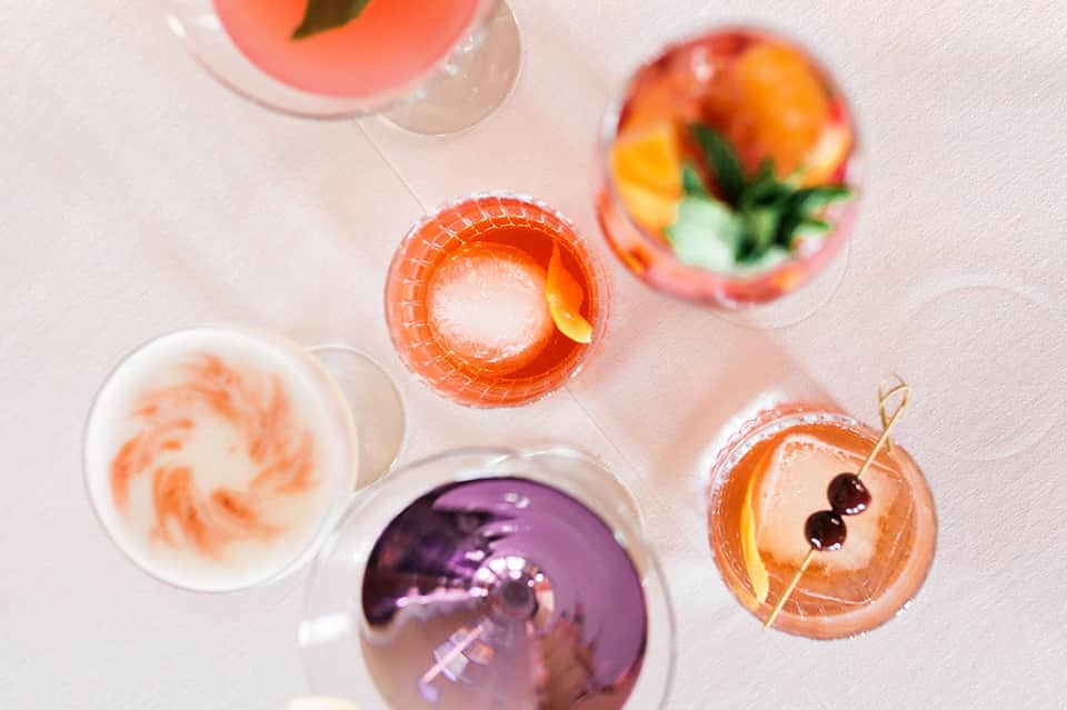 Colorful cocktails with fruit garnishes viewed from above on light surface