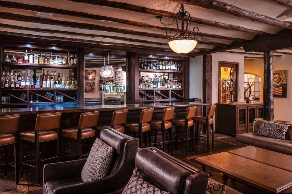 Upscale bar with dark wood beams, leather seating, and extensive liquor collection