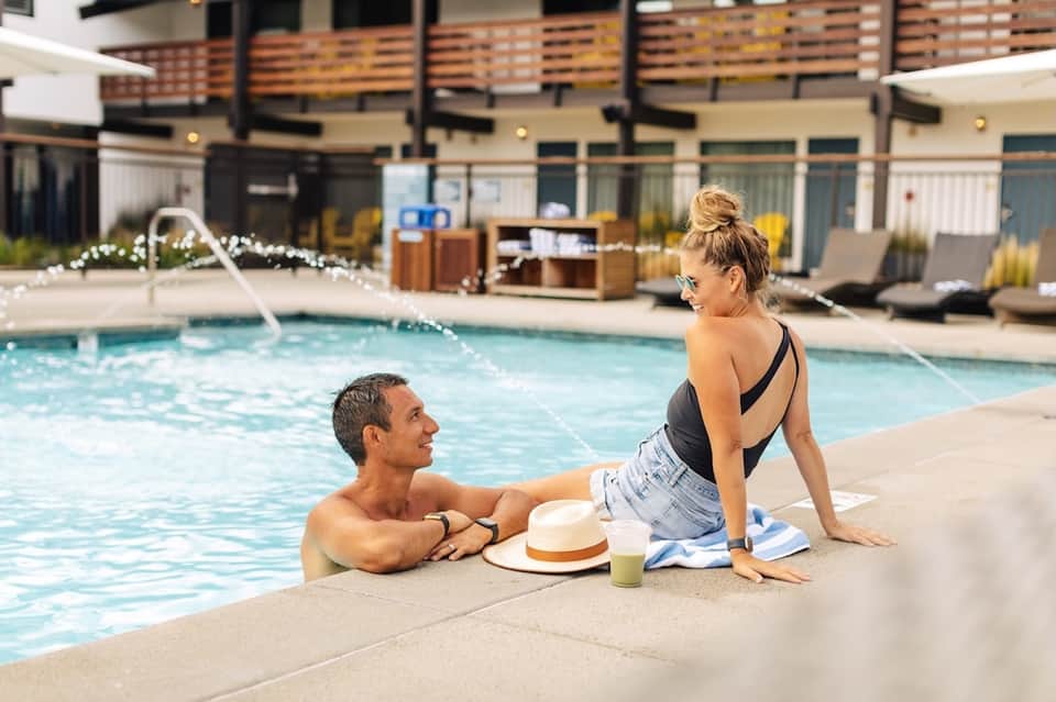 Couple enjoying the pool deck at a modern resort with contemporary architecture and landscaping