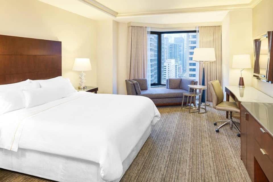 Upscale hotel suite with king bed, city skyline views, and modern furnishings