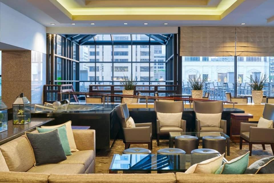 Elegant lounge with floor-to-ceiling windows, beige furnishings, and city views from high floor