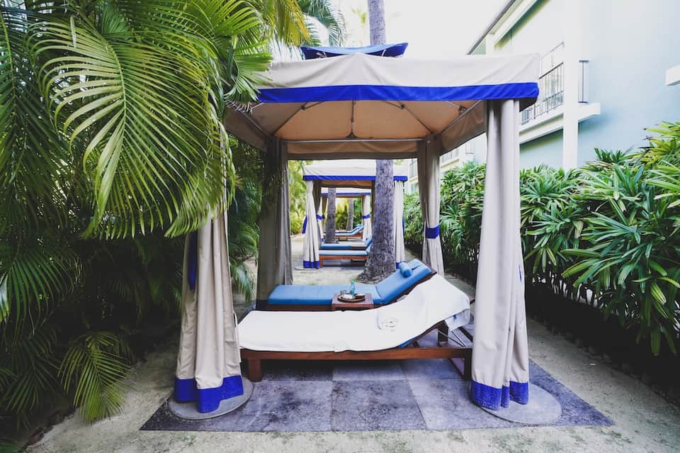 Tropical poolside cabana with blue and white striped canopy surrounded by palm trees