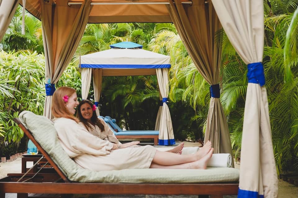 Woman relaxing in draped cabana bed surrounded by tropical palm plants