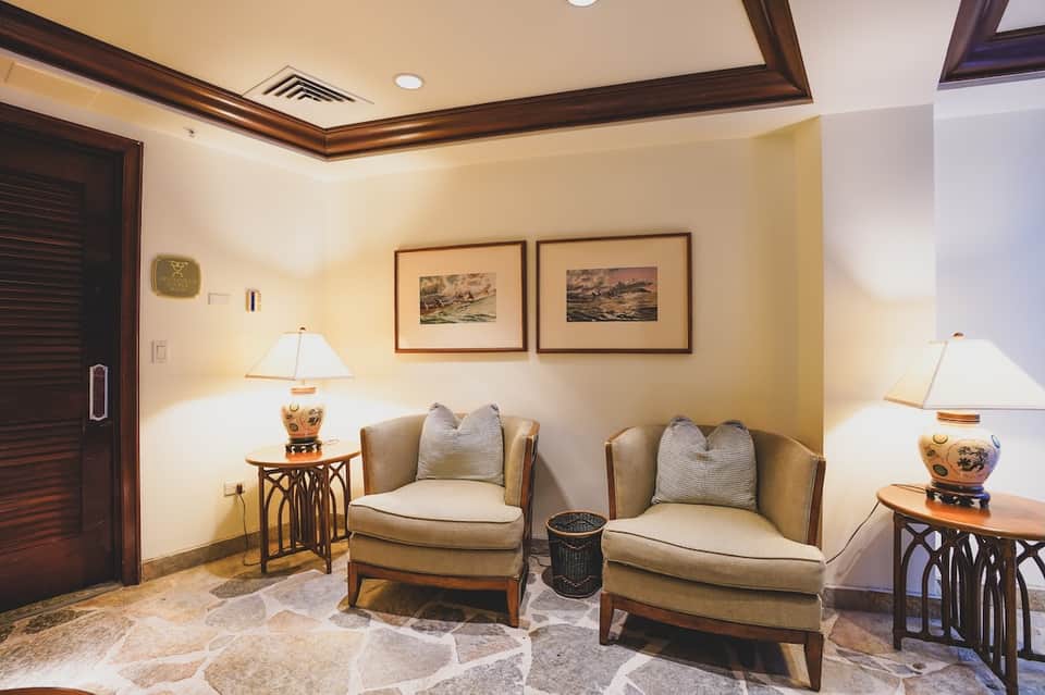 Elegant lounge with beige armchairs, table lamps, framed artwork, and decorative accents