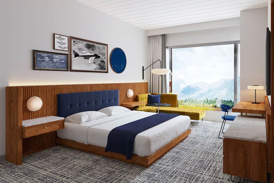 Contemporary hotel bedroom with wood bed frame, navy headboard, mountain view, and modern furnishings