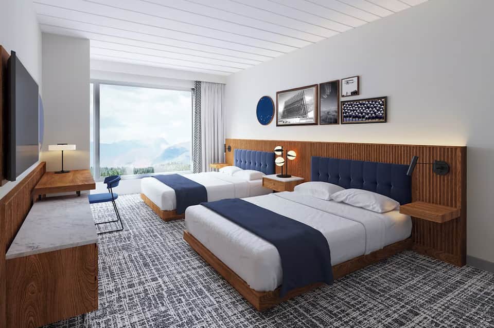 Modern hotel room with two queen beds, wooden headboards, and mountain view from large window