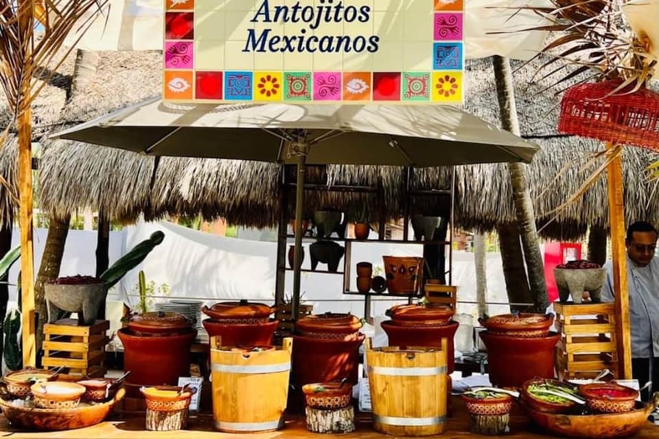 Mexican pottery shop display with colorful clay pots and traditional ceramics under thatched roof