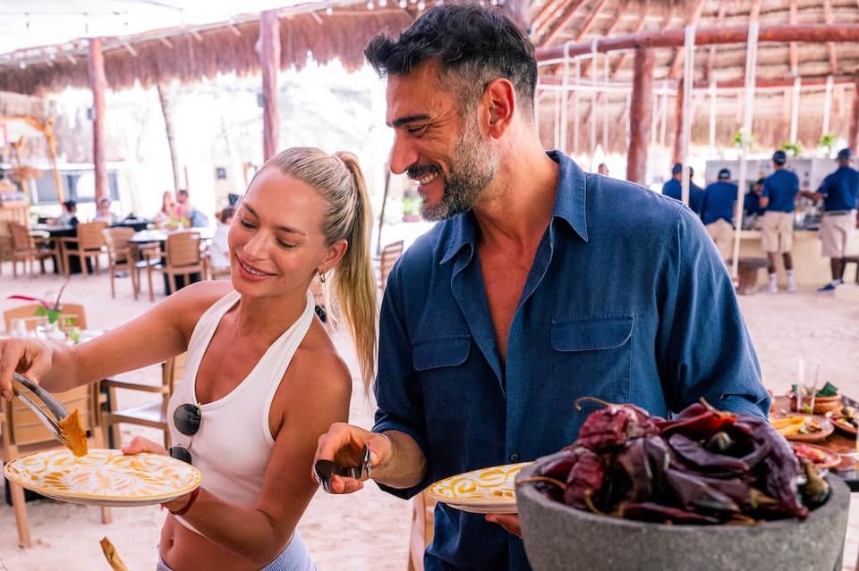 Couple enjoying casual beachfront dining with food and ocean view in background