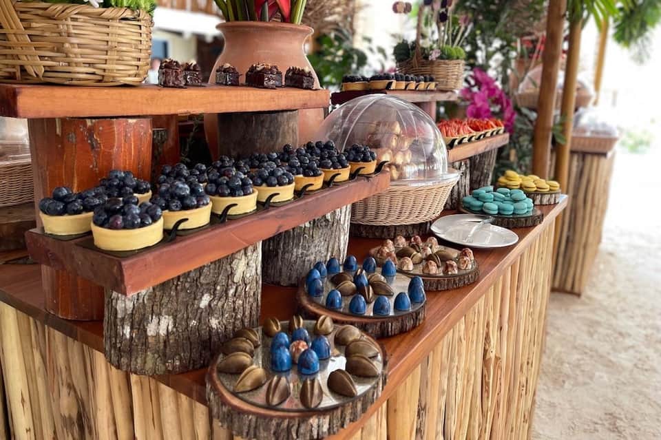 Rustic outdoor market display with blueberries, pastries, macarons, and decorative flowers