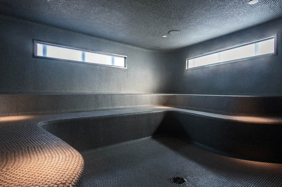 Empty sauna interior with bench seating and high windows for natural light