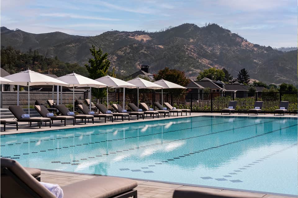 Resort swimming pool with lap lanes, white shade structures, and mountain landscape views