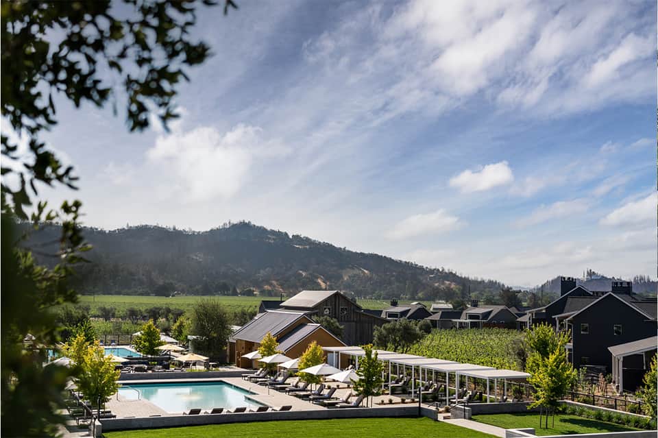 Vineyard resort pool with mountain views, lounge chairs, and modern architecture