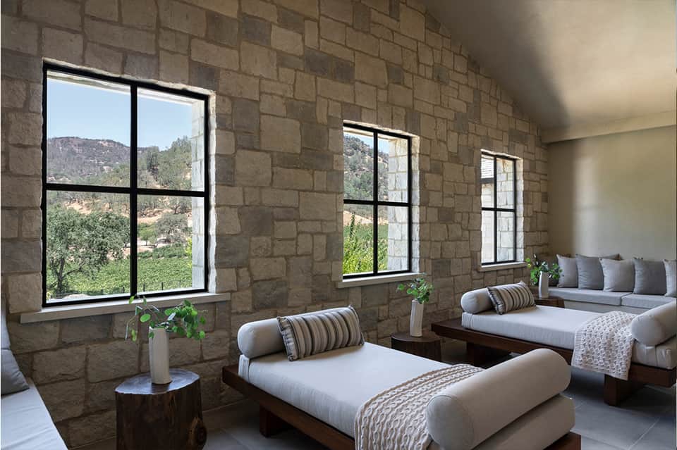 Spa relaxation room with stone walls, large windows, and upholstered daybed seating
