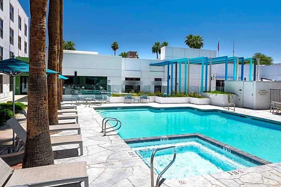 Resort pool area with turquoise water, palm trees, and contemporary architecture