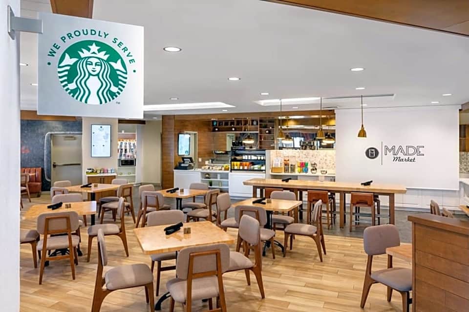 Contemporary cafe interior with Starbucks signage, wooden furniture, high ceilings, and Made Market branding