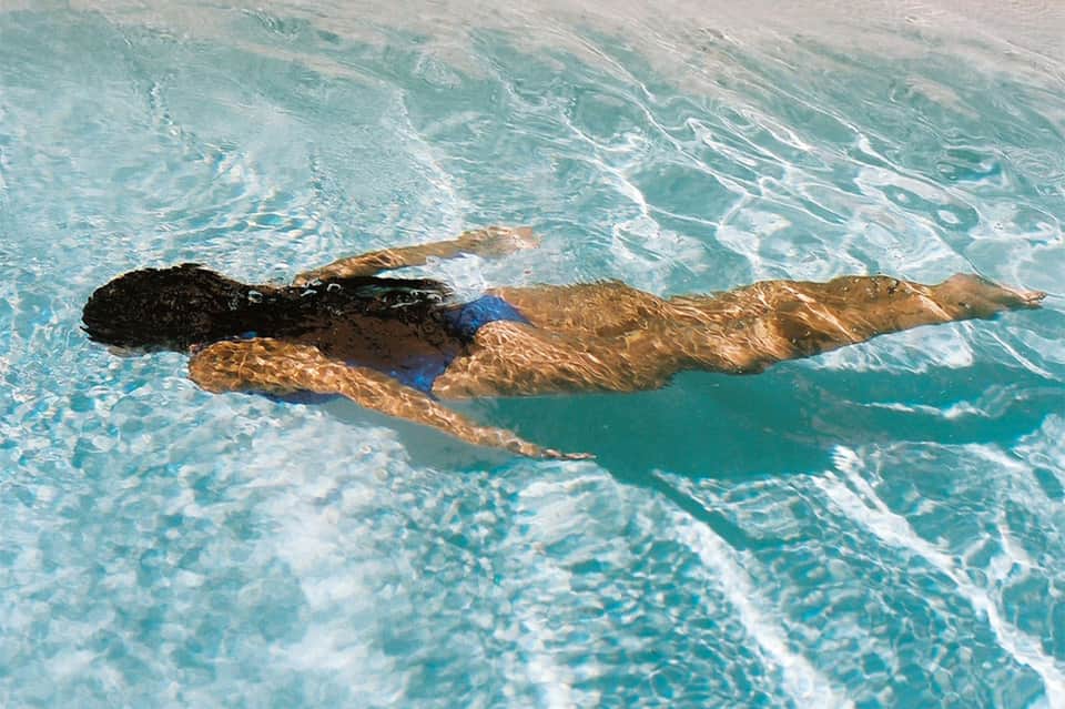 Swimmer doing freestyle stroke in clear turquoise lap pool water
