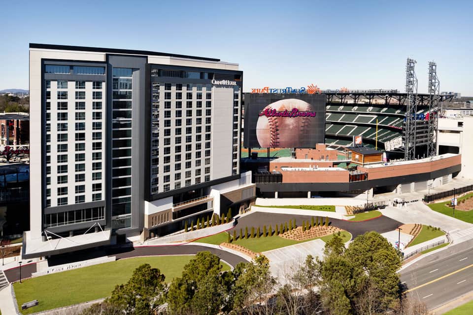 Modern hotel tower next to baseball stadium with sports signage and manicured grounds
