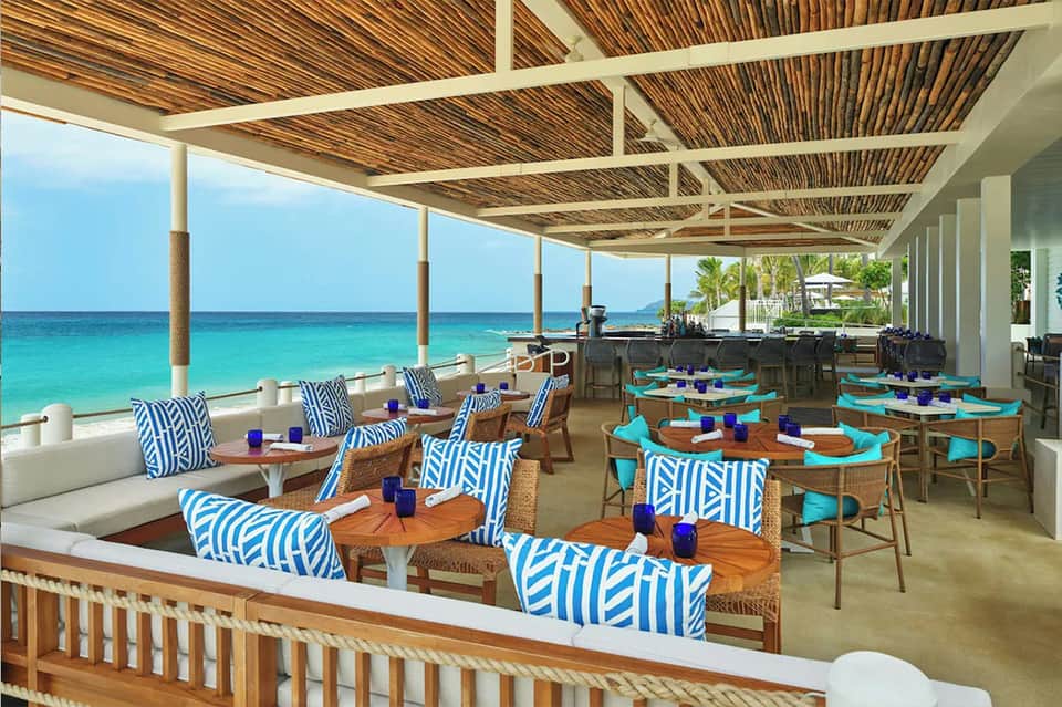 Elegant beachfront dining area with turquoise ocean views and blue patterned furniture