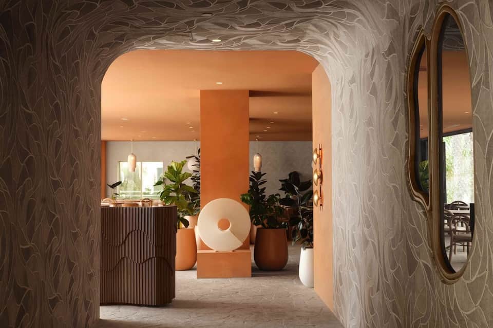 Elegant corridor with textured walls, orange accent column, and artistic decor