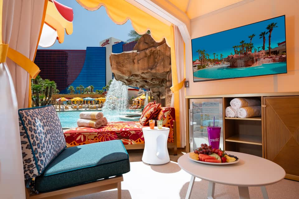 Poolside cabana interior with colorful décor, view of waterfall and pool area through window