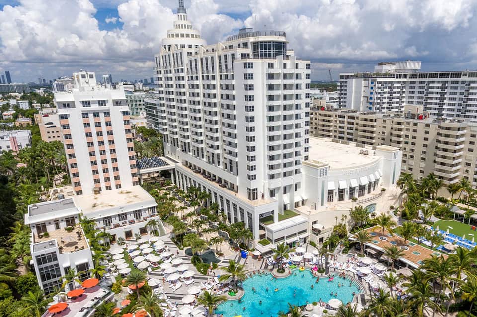 Aerial view of beachfront resort with pool, towers, and oceanfront deck