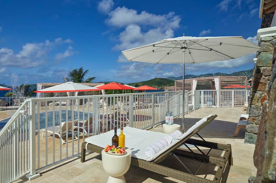 Oceanview terrace with lounge chair, white umbrellas, and mountain backdrop