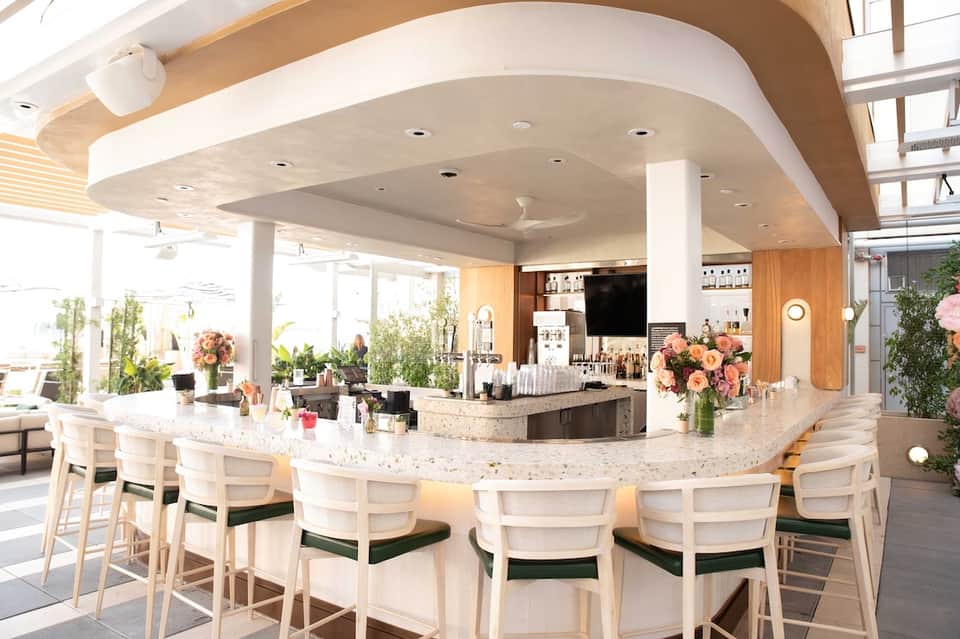 Modern curved reception desk with white chairs, marble countertop, and fresh floral arrangements